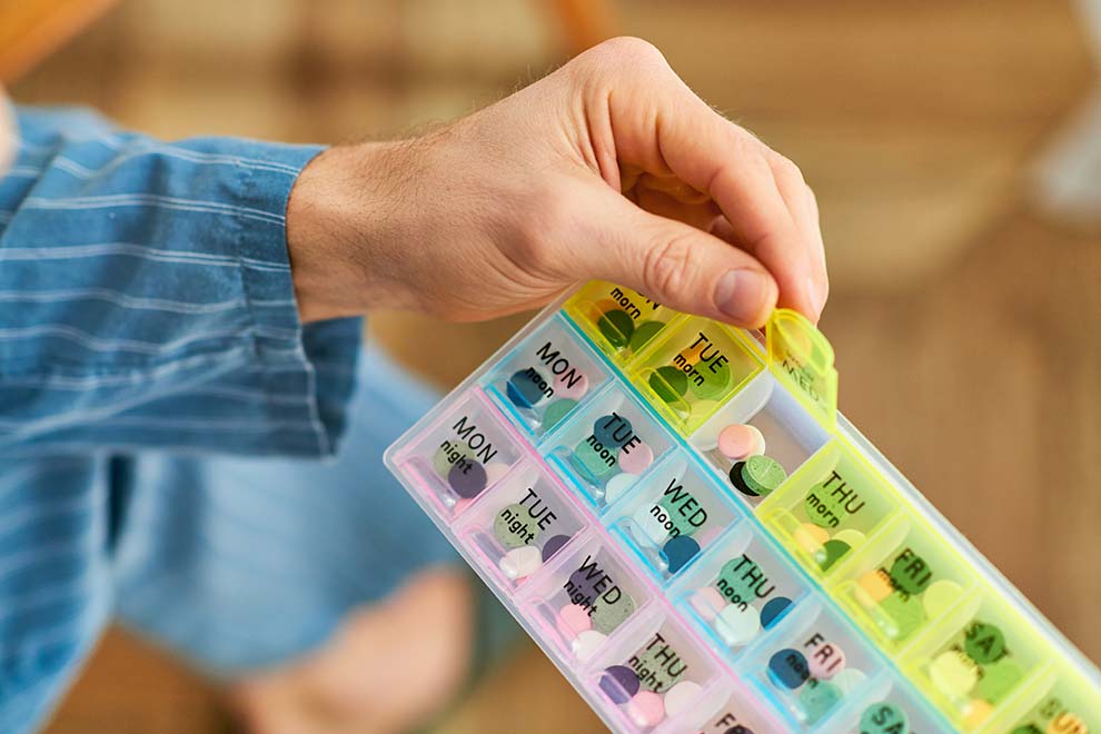 Pessoa segurando organização de medicamentos semanal