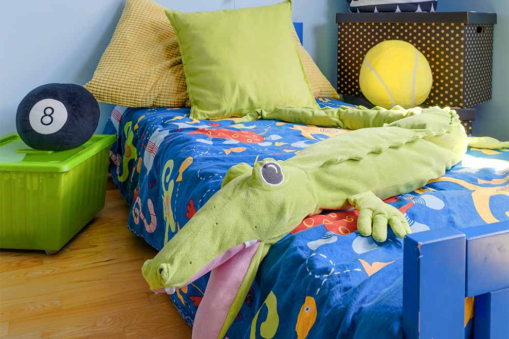 Cama infantil com edredom colorido e crocodilo de pelúcia