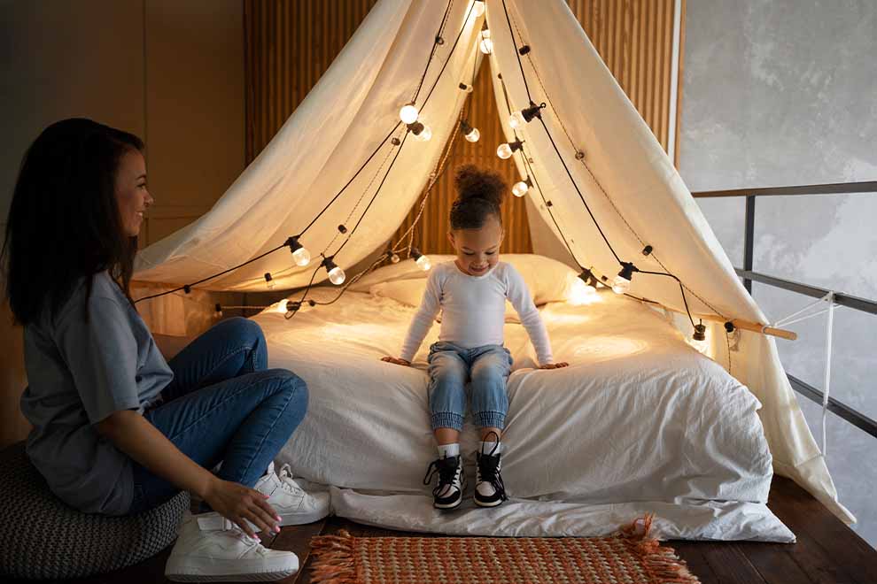 Mãe e filha brincando em uma cabana com luzes suaves.