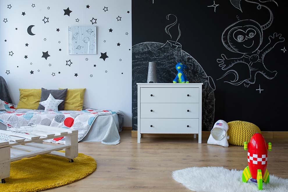 Quarto infantil decorado com estrelas e brinquedos coloridos.