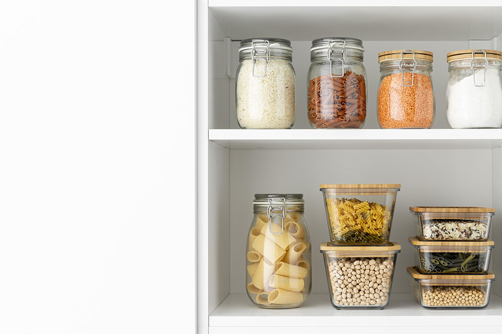 Armário de cozinha com diversos potes com temperos, arroz e macarrões. 