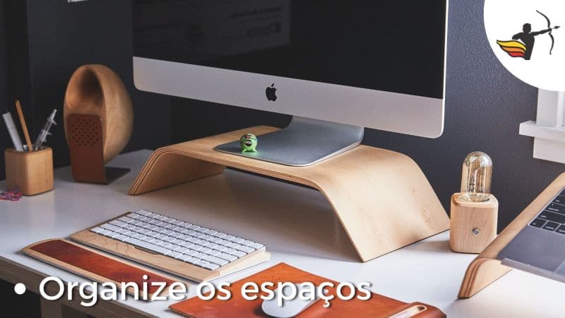 Escrivaninha de escritório organizada com aparelhos eletrônicos e peças decorativas.