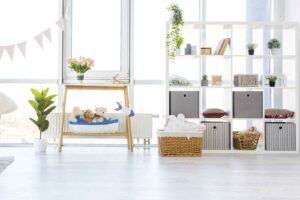 Sala de estar, com uma mesa, diversos vasos com plantas e uma estante modular, durante o dia.