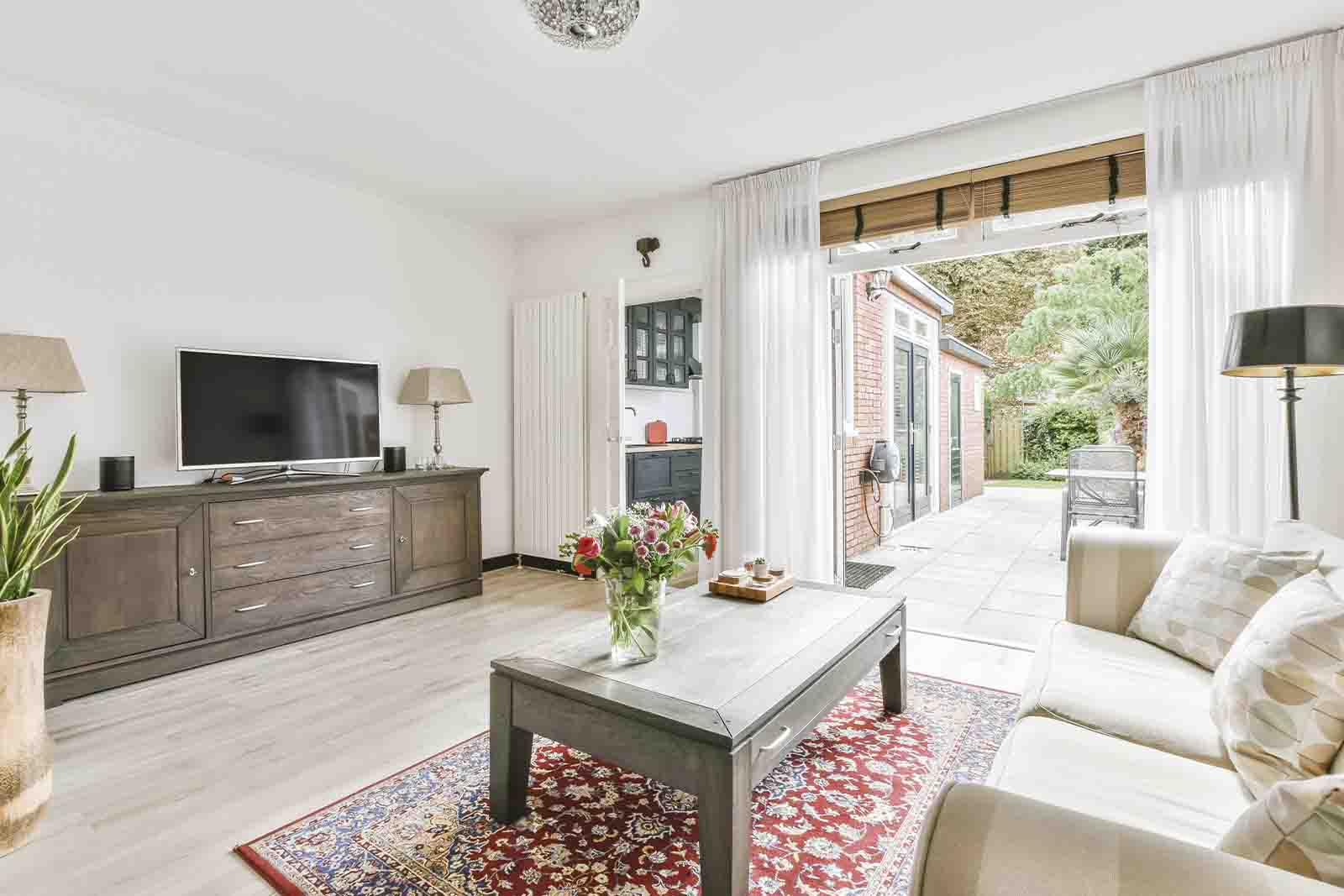 Sala de estar com raque, tv, mesa de centro, sofá, tapete e diversas luminárias.