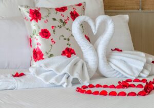 cama de casal com decoração romântica composta por dois cisnes feitos de toalha