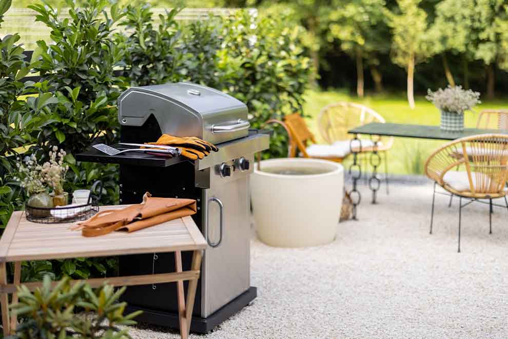 Churrasqueira em um jardim com mesas e cadeiras.