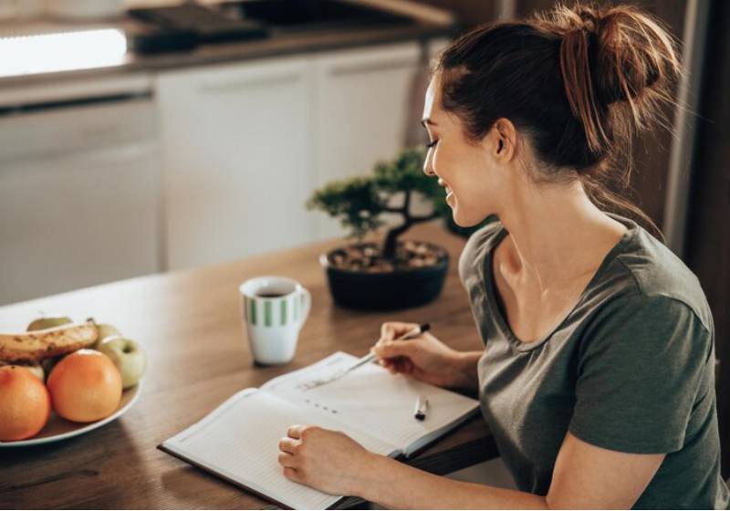 Modelo senta na mesa com um caderno conferindo as anotações