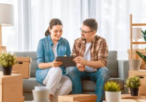 imagem de casal sentando em um sofá mexendo em um tablet