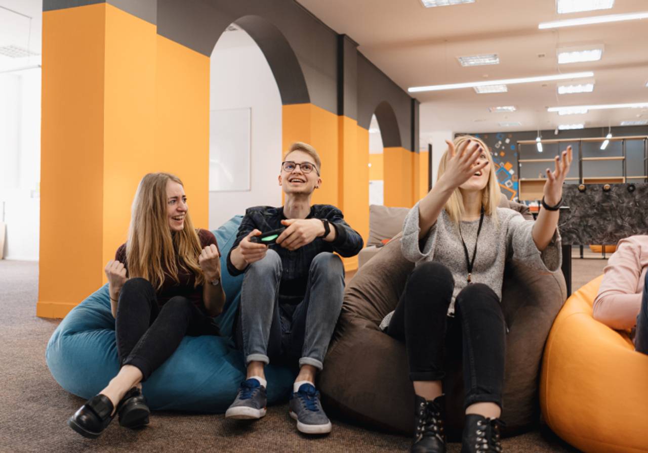 Sala com três pessoas senta em pufs