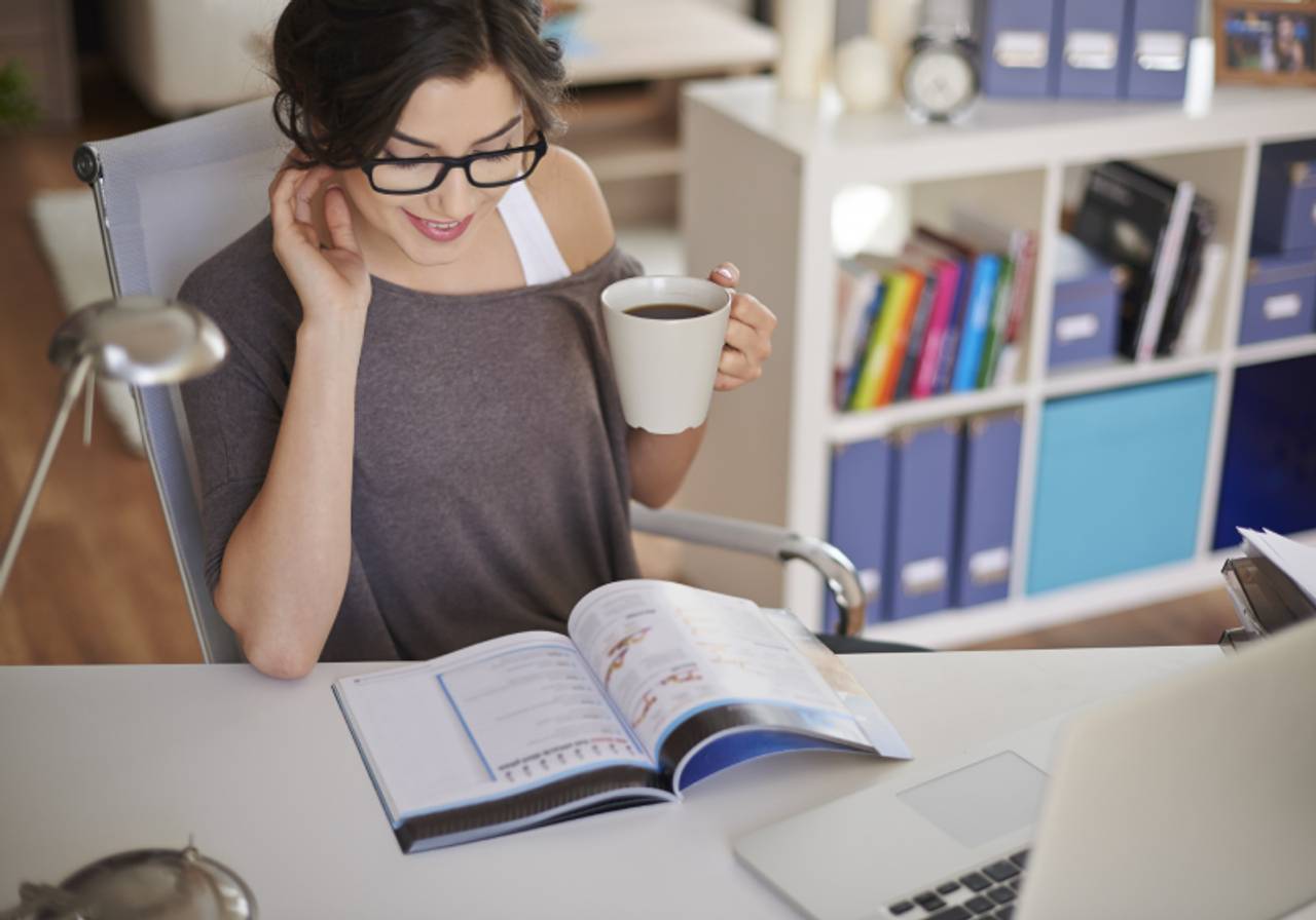 vista superior de mulher estudando com uma xicara de café na mão