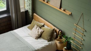 Quarto com parede verde, cama e detalhes em madeira no quarto.