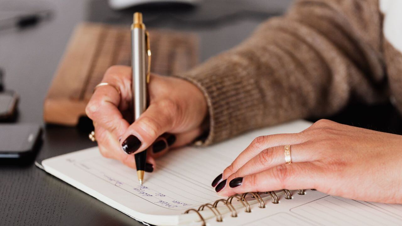 Pessoa realizada anotações em sua agenda.