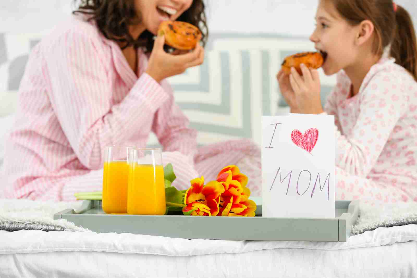 Mãe e filha tomando cafe da manha na cama