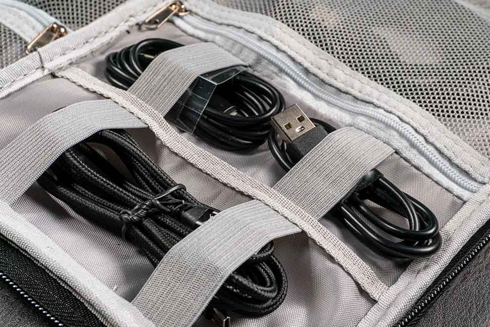 Bolsa organizadore para fio de eletronicos aberto em cima de uma mesa de madeira.