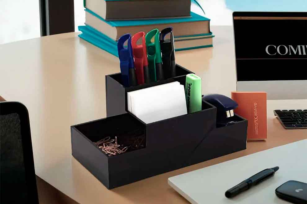 Organizador de escritorio em cima de uma mesa de madeira com itens de escritorio como post it, clip de papel e canetas.