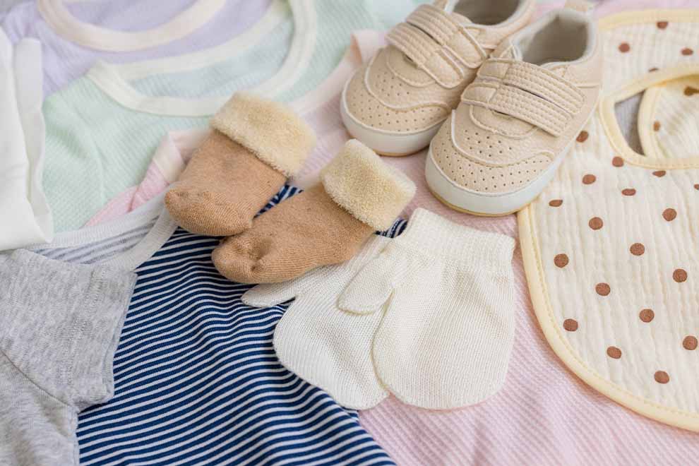 roupas de bebê com dois pares de sapatinhos em cima