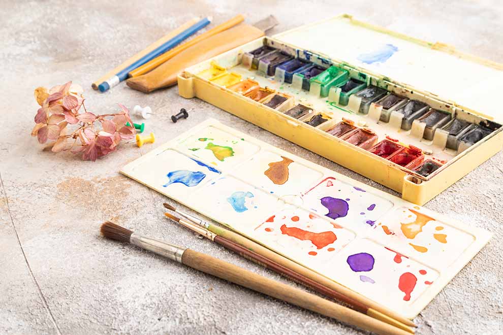 Conjunto de aquarelas e pinceis sobre mesa
