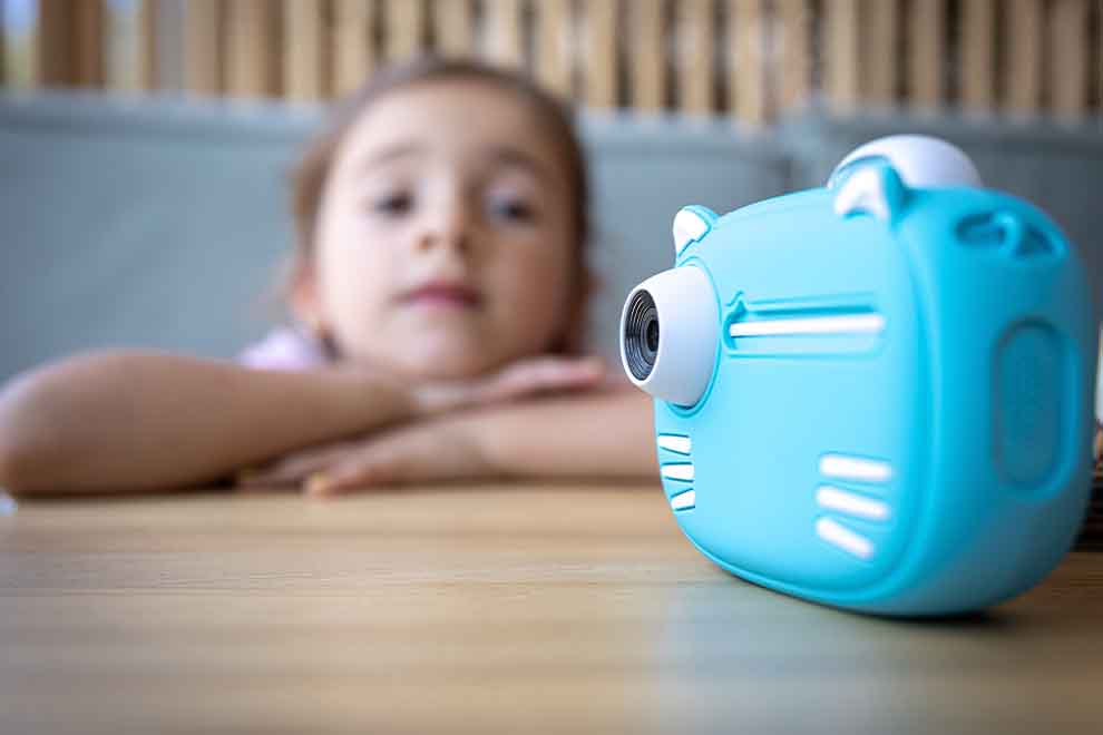 Câmera infantil azul com criança ao fundo.