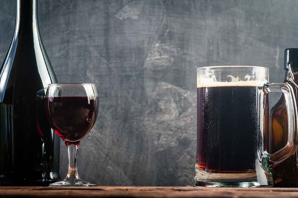 Cerveja escura em caneca ao lado de taça de vinho