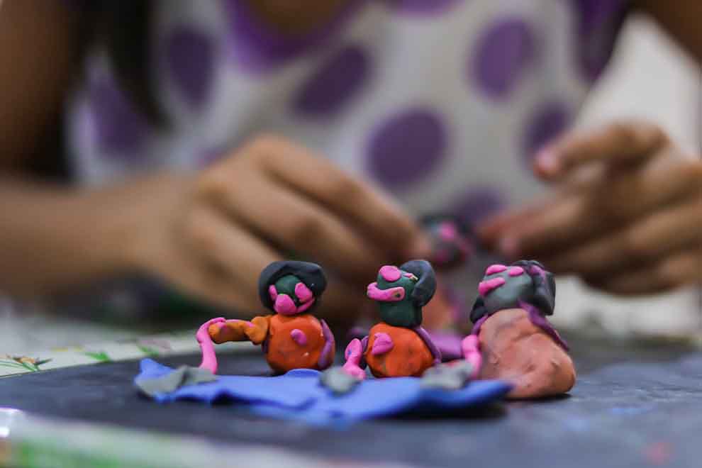 Criança moldando figuras de massinha colorida