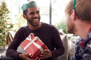 Homem sorrindo segurando presente em festa de Natal.