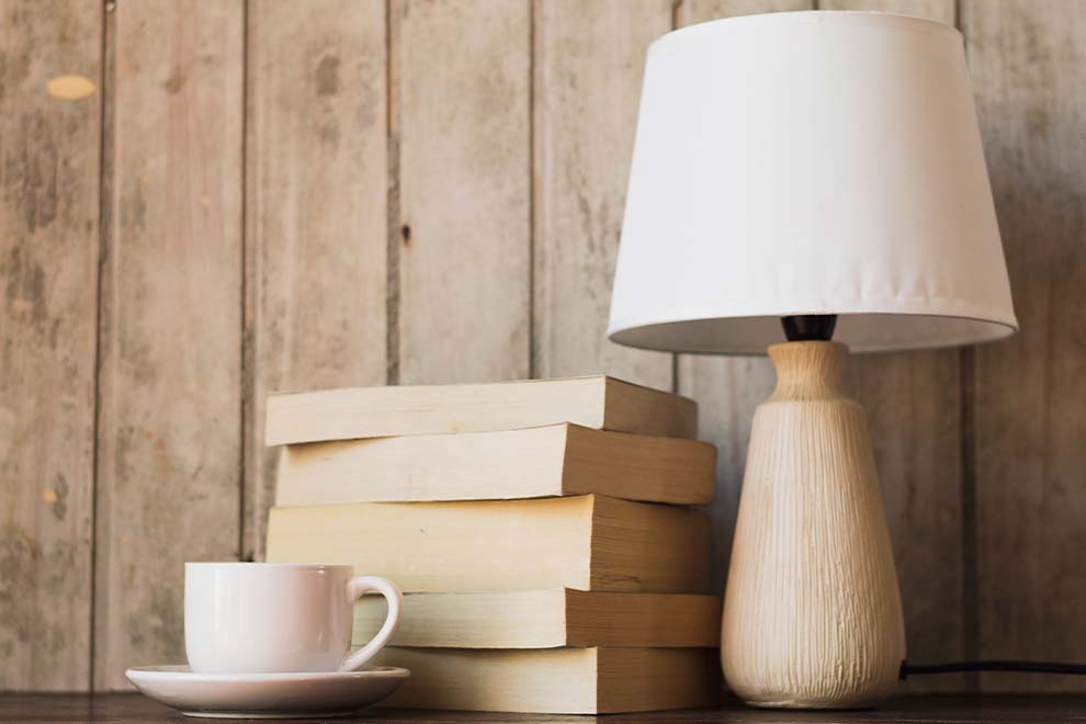 Luminária ao lado de livros e xícara de café