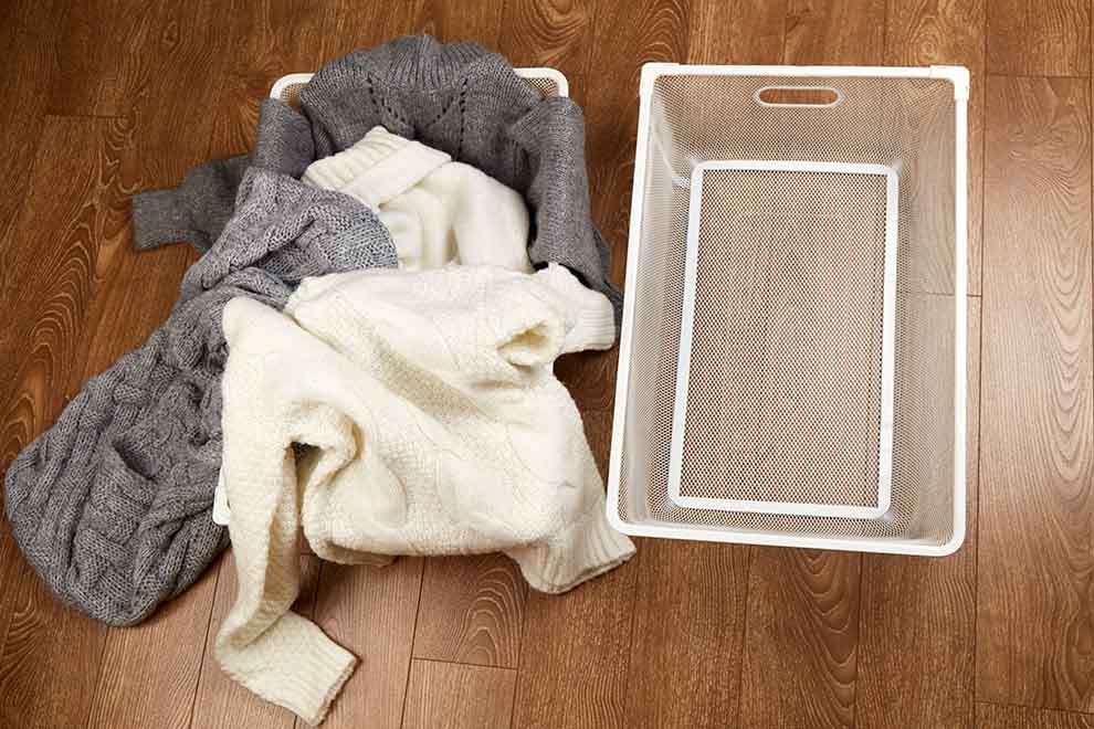 Malhas de lã em cestinho branco sobre piso de madeira