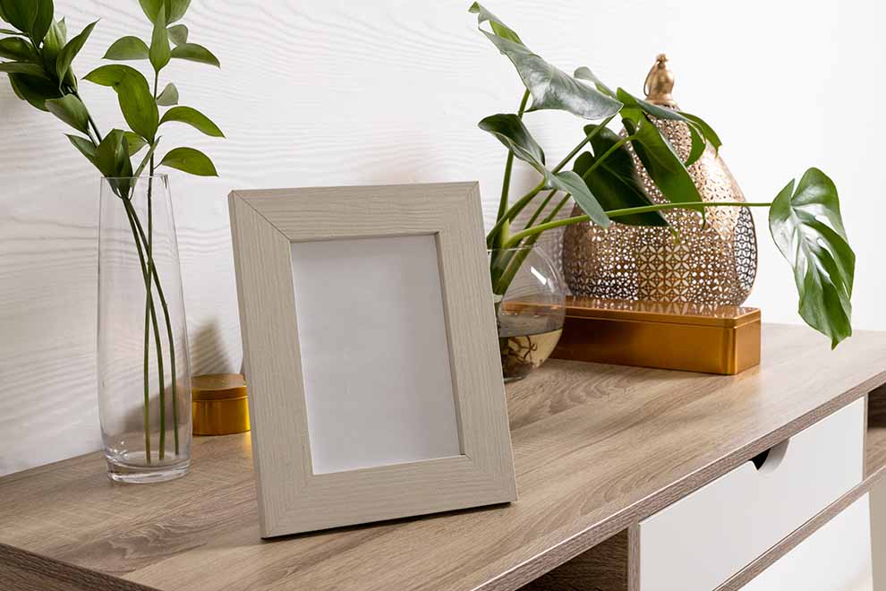 Moldura vazia em mesa com plantas decorativas