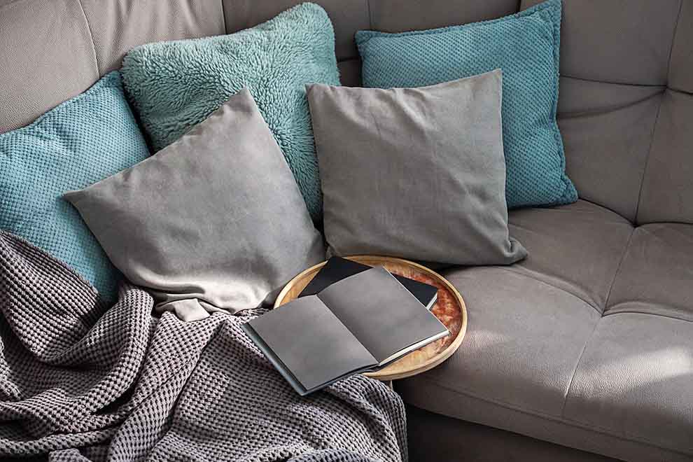 sofá confortável com almofadas e livro aberto