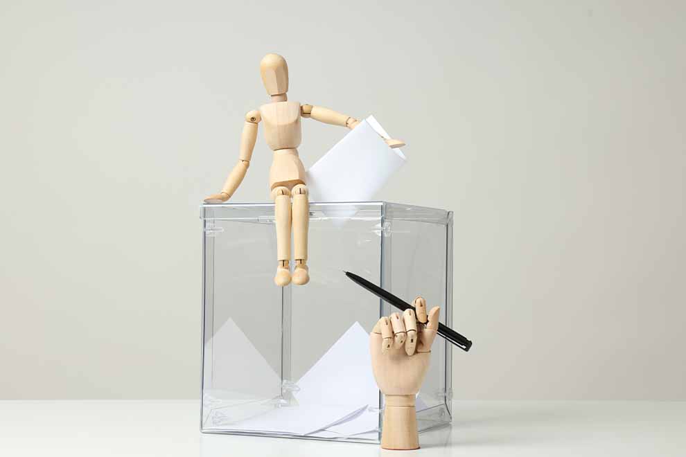 boneco de madeira sentado sob urna transparente