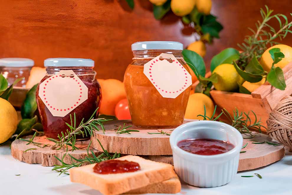 mesa com potes de geleias e frutas ao fundo