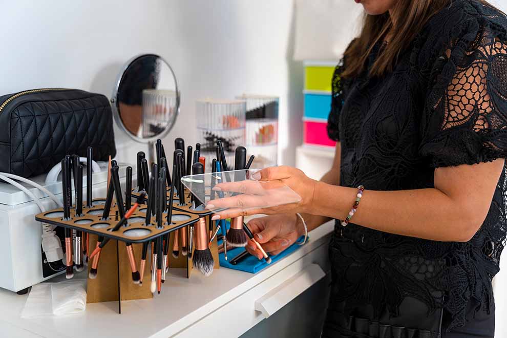 moça organizando pinceis de maquiagem em sobre penteadeira