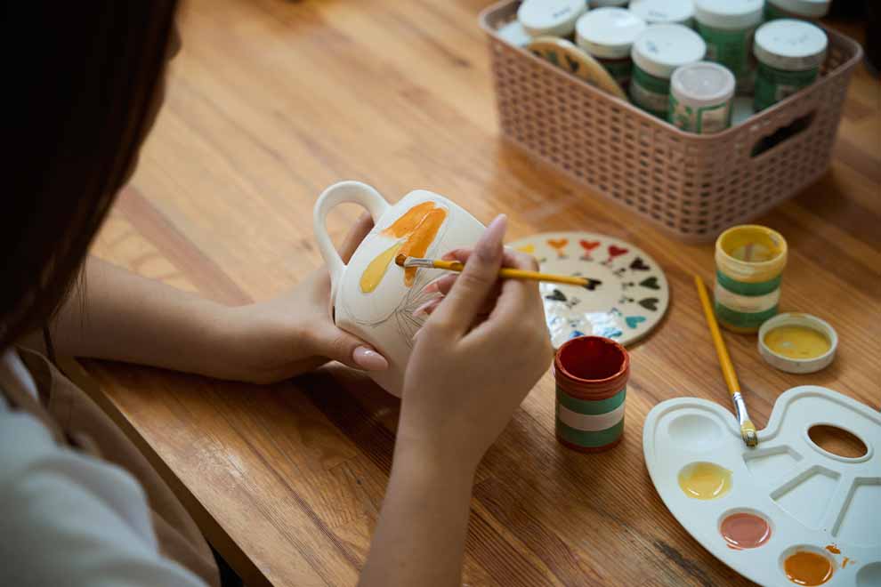 Mulher pintando canecas brancas de amarelo