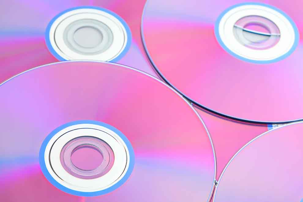 Vários discos de CD e DVD empilhados juntos, um em cima do outro.