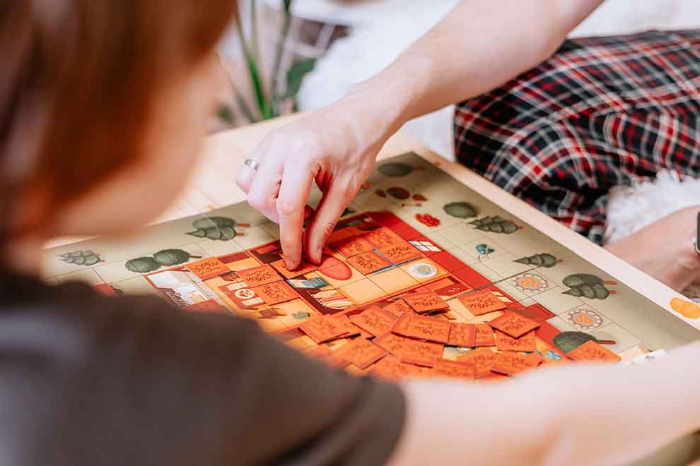 Pai e filho brincando com jogos de tabuleiro em uma mesa de centro na sala em um dia ensolarado.