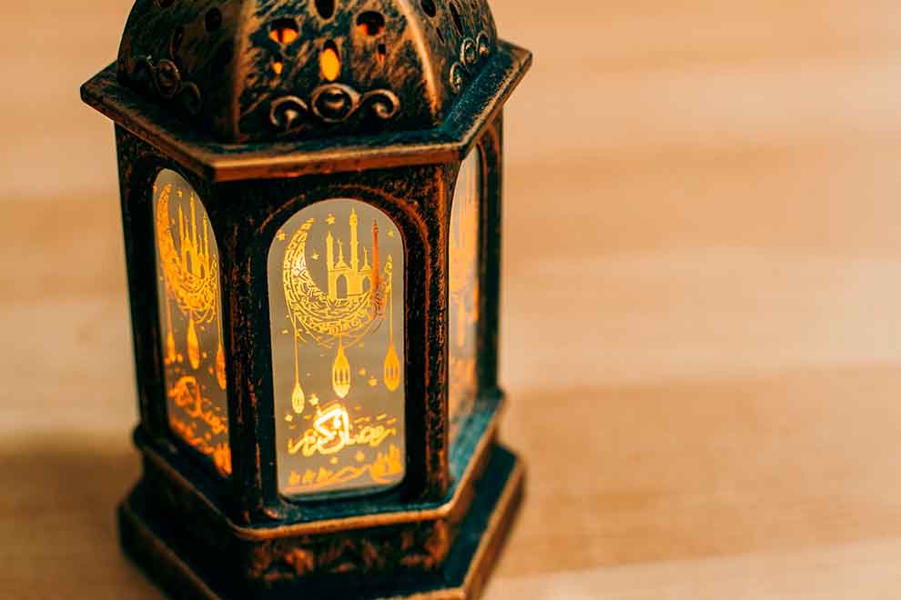 Luminária decorativa acessa em cima de uma mesa de madeira.