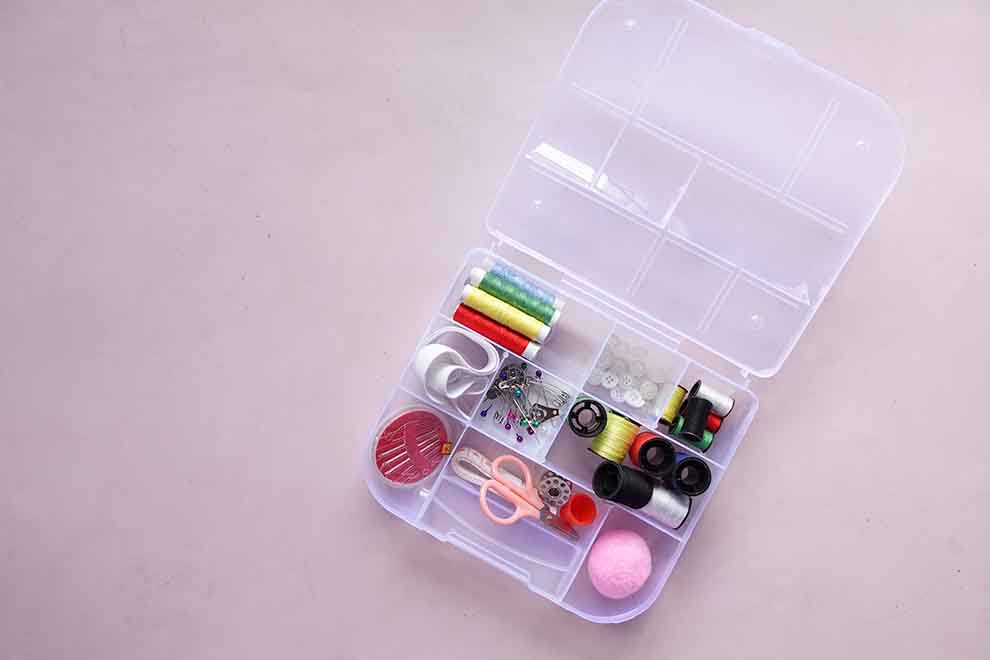 Caixa organizada com materiais de costura variados.